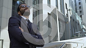 African american businessman standing near office building, optimistic outlook