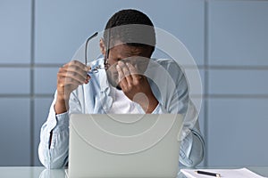 African american businessman taking off glasses, suffering from dry eyes.