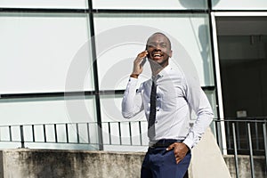 African american businessman walking and talking with mobile phone in the city