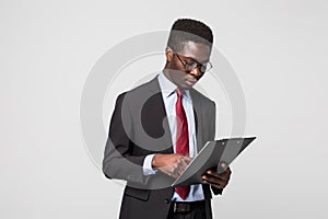 African American businessman writing on a clipboard on grey