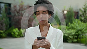 African American businesswoman chatting with mobile app outdoors ethnic girl using phone in city business woman