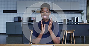 African american businesswoman having video chat smiling and clapping in workplace kitchen