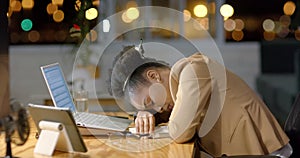 African American businesswoman rests her head on a desk at night, with copy space