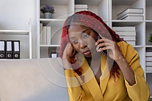 African American businesswoman talking on the phone while working in the office with stress