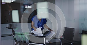 African american businesswoman unrolling technical drawing on table in meeting room