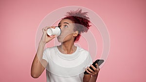 African American businesswoman using smartphone drinks coffee from paper cup