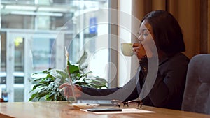 African american businesswoman working with laptop and papers. Girl drinking coffee