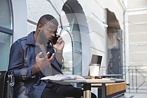 African american bussines man having a heated arguement with colleague over the phone photo