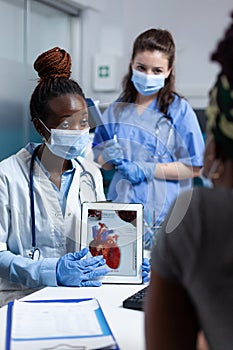 African american cardiologist doctor holding tablet showing heart radiography