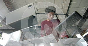 African american casual businessman with documents using tablet on glass table, slow motion