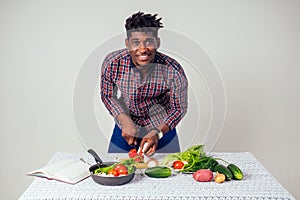 African american chef kitchener holding a frying pan wizard man cooking magic flying food salad, carrot, garlic, onion