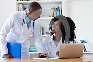 African american chief physician with young female doctor at work