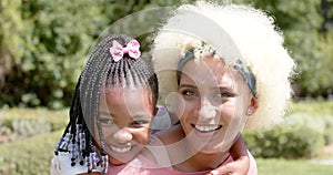 African American child with braided hair hugs a young biracial woman with curly hair