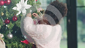 African American child decorated with ornament on Christmas tree at Christmas and New Year festival at home. Xmas celebration