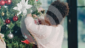 African American child decorated with ornament on Christmas tree at Christmas and New Year festival at home. Xmas celebration