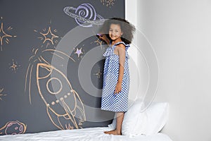 African-American child drawing rocket with chalk on wall