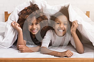 African-american child girls lying under blanket on bed