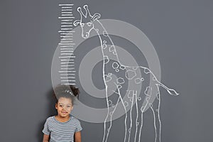 African-American child measuring height near chalk giraffe drawing