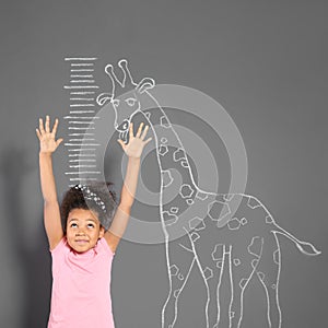 African-American child measuring height near chalk giraffe drawing on wall