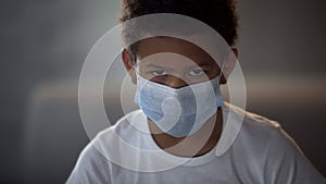 African American child in medical mask looking in camera with sad eyes, epidemic
