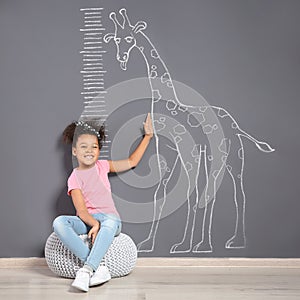 African-American child near grey wall with chalk giraffe drawing