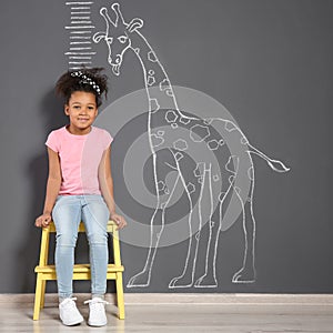 African-American child near grey wall with chalk giraffe drawing