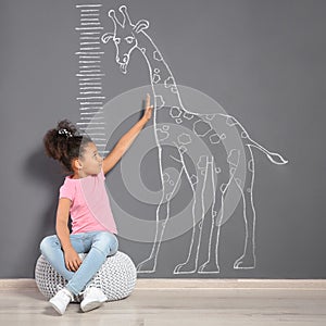 African-American child near grey wall with chalk giraffe drawing