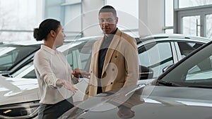 African American couple buying new car in auto showroom woman seller manager dealer saleswoman consult man client to