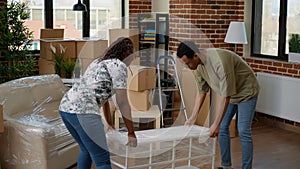 African american couple carrying furniture to decorate new home