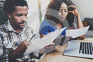 African american couple checking home bills together at the wooden table.Young black man and his girlfriend using laptop