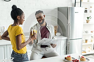 african american couple clinking with glasses of orange juice