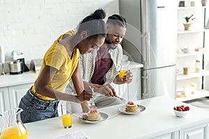 african american couple eating pancakes and drinking orange juice
