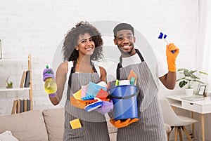 African-american couple holding cleaning tools and detergents