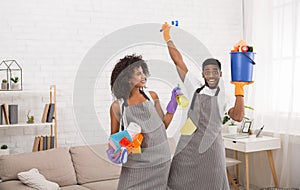 African-american couple holding cleaning tools and detergents