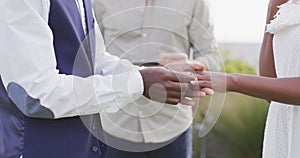 African american couple holding hands and putting ring during wedding