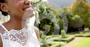 African american couple holding hands and smiling at their wedding in sunny garden, in slow motion