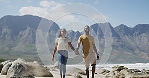 African american couple holdings hands and walking at the beach