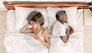 African-american couple ignoring each other in bed