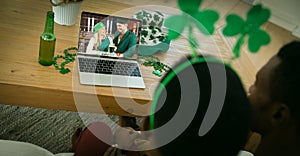 African american couple making st patrick\'s day video call to friends in costumes on laptop at home