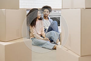 African American couple moving new home. man, woman are sitting among boxes talking mortgage