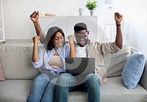African american couple sitting on couch, using pc