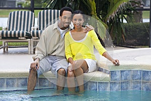 African American Couple Sitting By A Swimming Pool