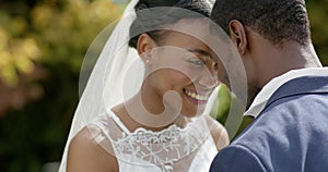 African american couple smiling and touching heads at their wedding in sunny garden, slow motion