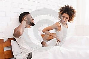 African-american couple suffering from back and neck ache in bed