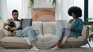 African American couple technology video game addict family with two laptops playing online on couch home woman work