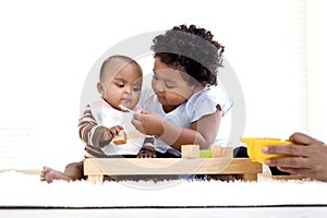 African American curly hair girl trying to feed her little sister with spoon of food, infant eating healthy homemade baby food,