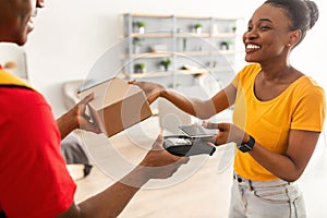 African American Customer Woman Paying Delivery Guy Using Phone Indoors