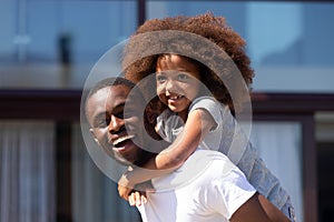 African American dad carry on back funny little daughter