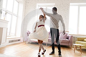 African American dad dancing with small daughter at home photo