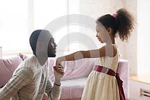 African American dad kneel kiss hand of biracial daughter